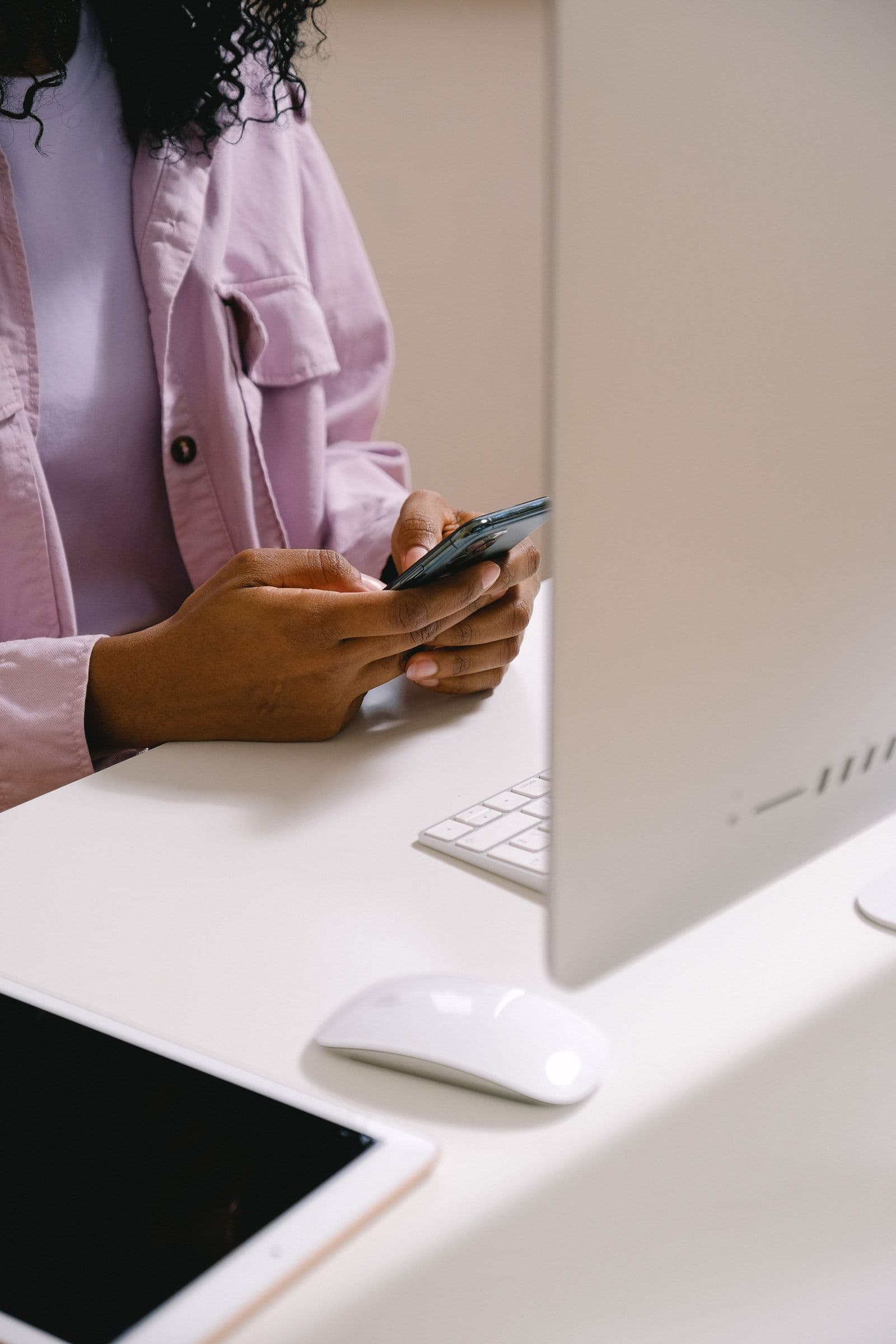 Hands typing a message on a phone at a desk