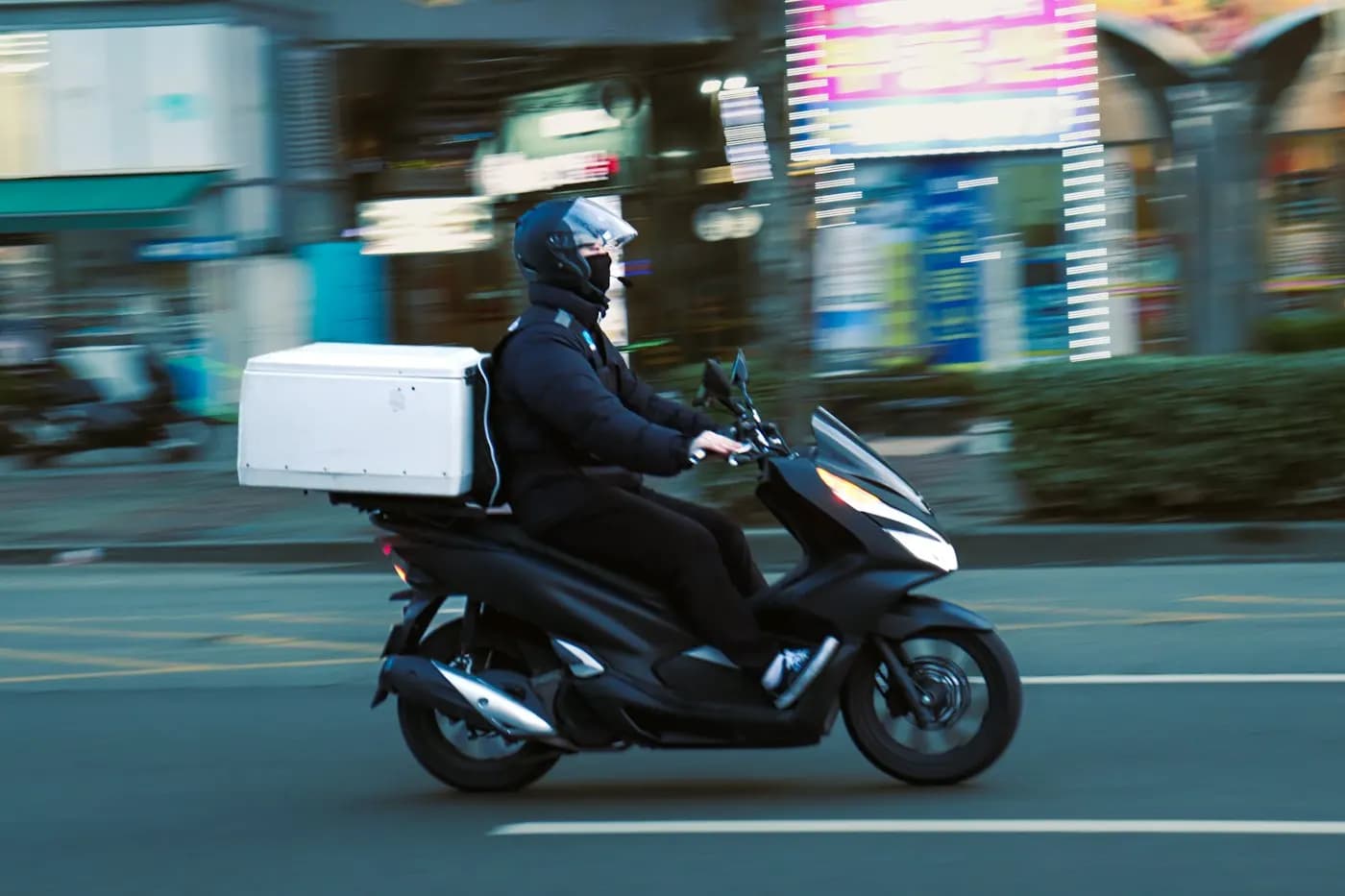 A rider on a scooter with a delivery box
